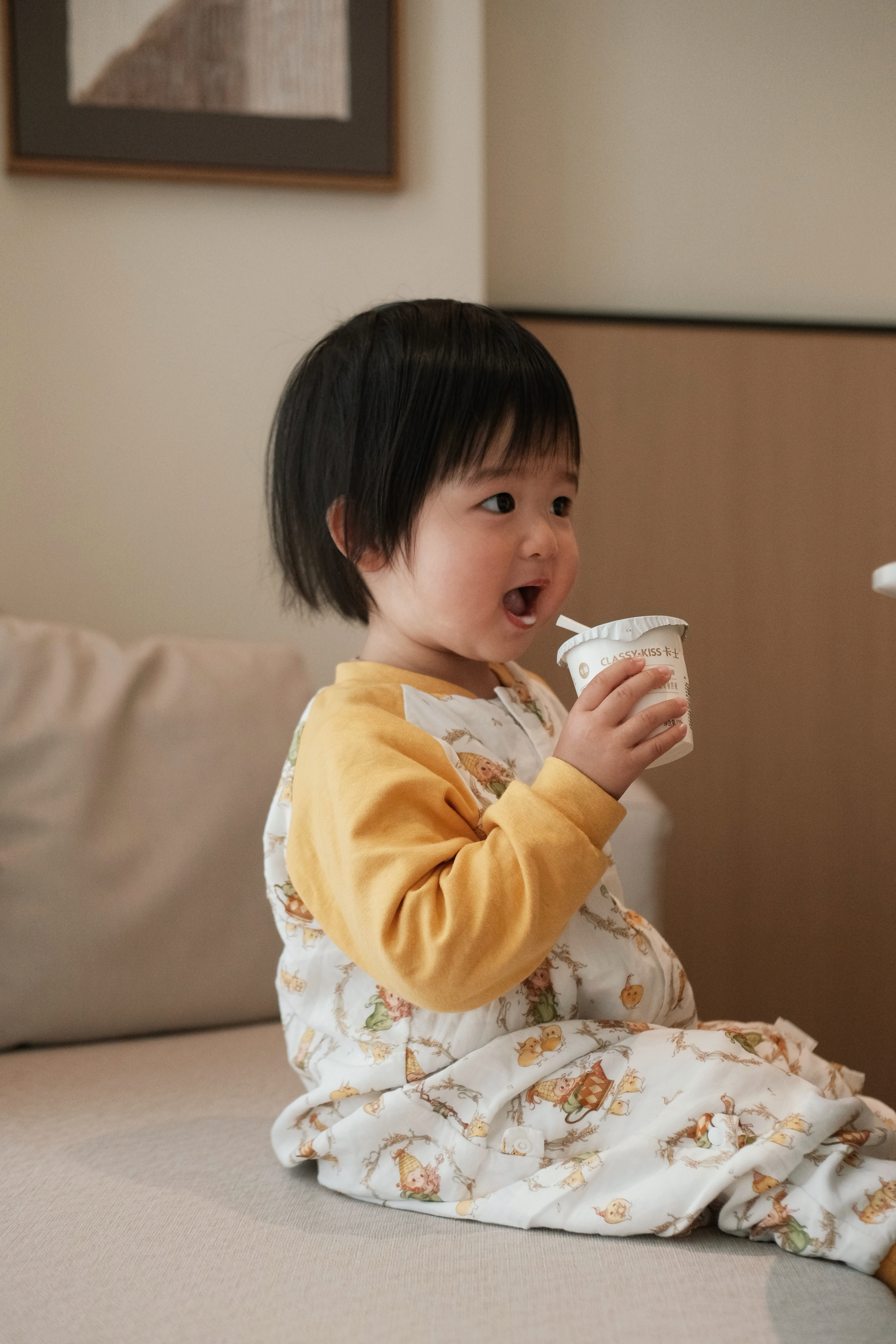 孩子穿着黄色睡袋喝饮品