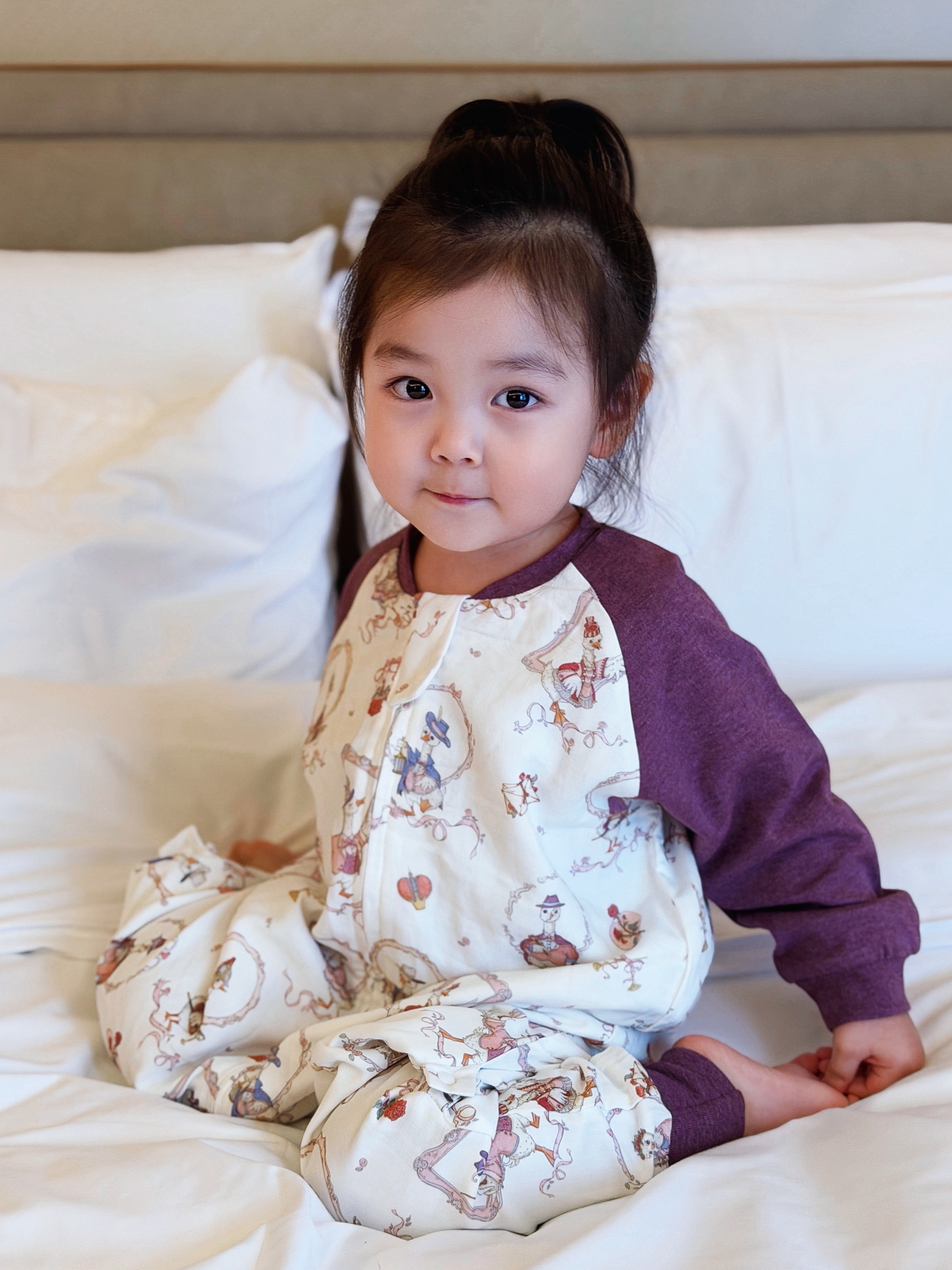 孩子穿着紫色睡袋坐在床上