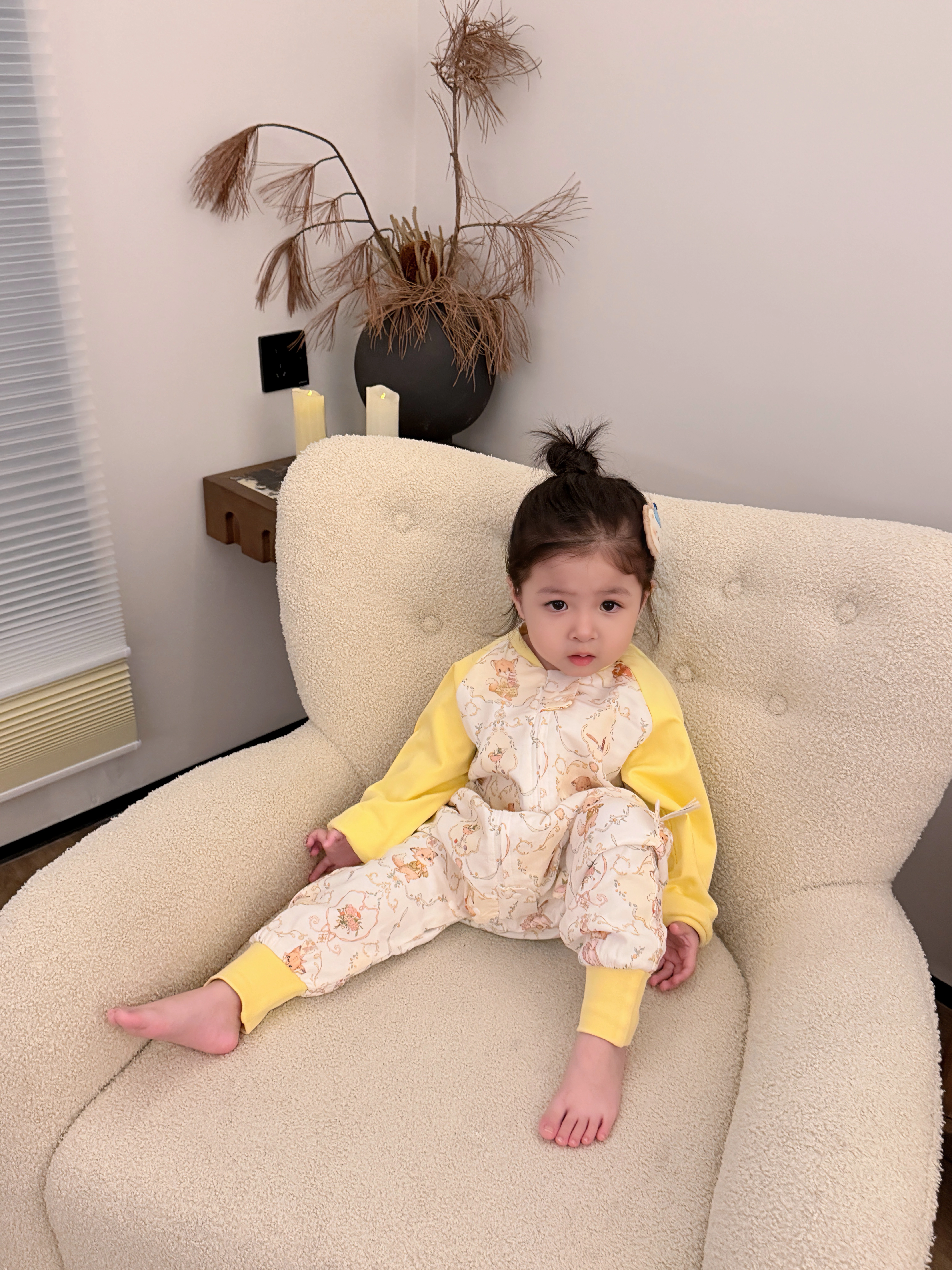 孩子穿着黄色睡袋坐在柔软座椅上
